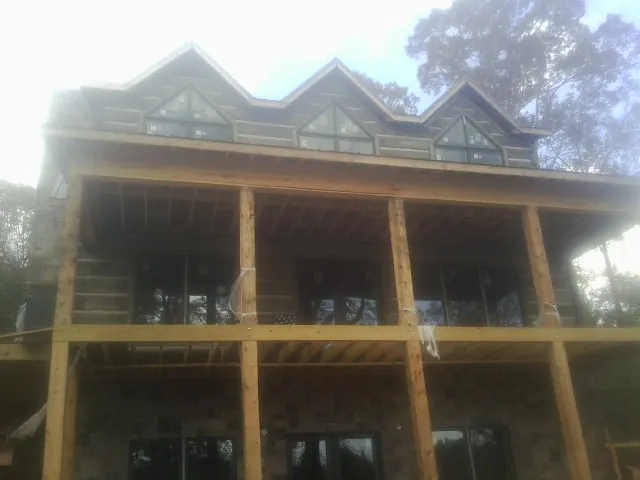 Dormers and porch framing on a large log home under construction — Roof Coating work by our crew in Edgewater
